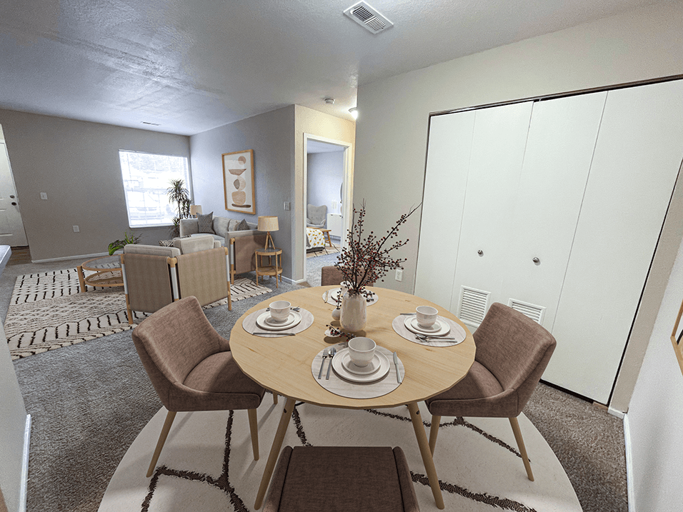 a dining area with a table and chairs and a living room in the background