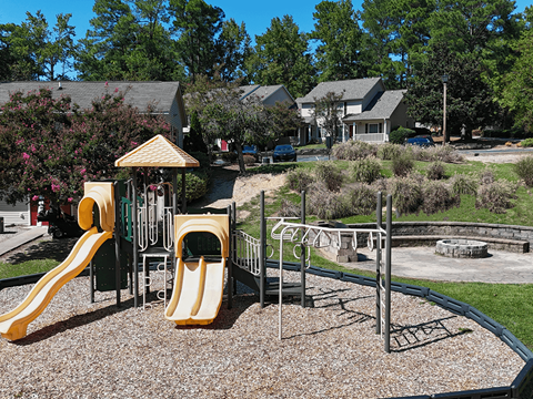A playground with a yellow slide and a green and yellow playhouse.