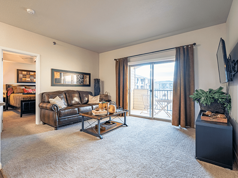 A living room with a brown leather couch and a grey carpet.