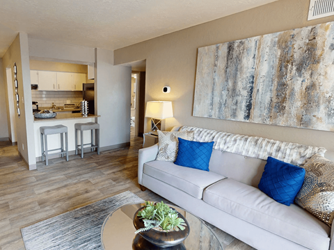 A living room with a couch, a table, and a painting on the wall.