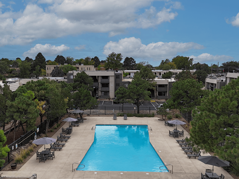 A large swimming pool surrounded by lounge chairs and umbrellas.