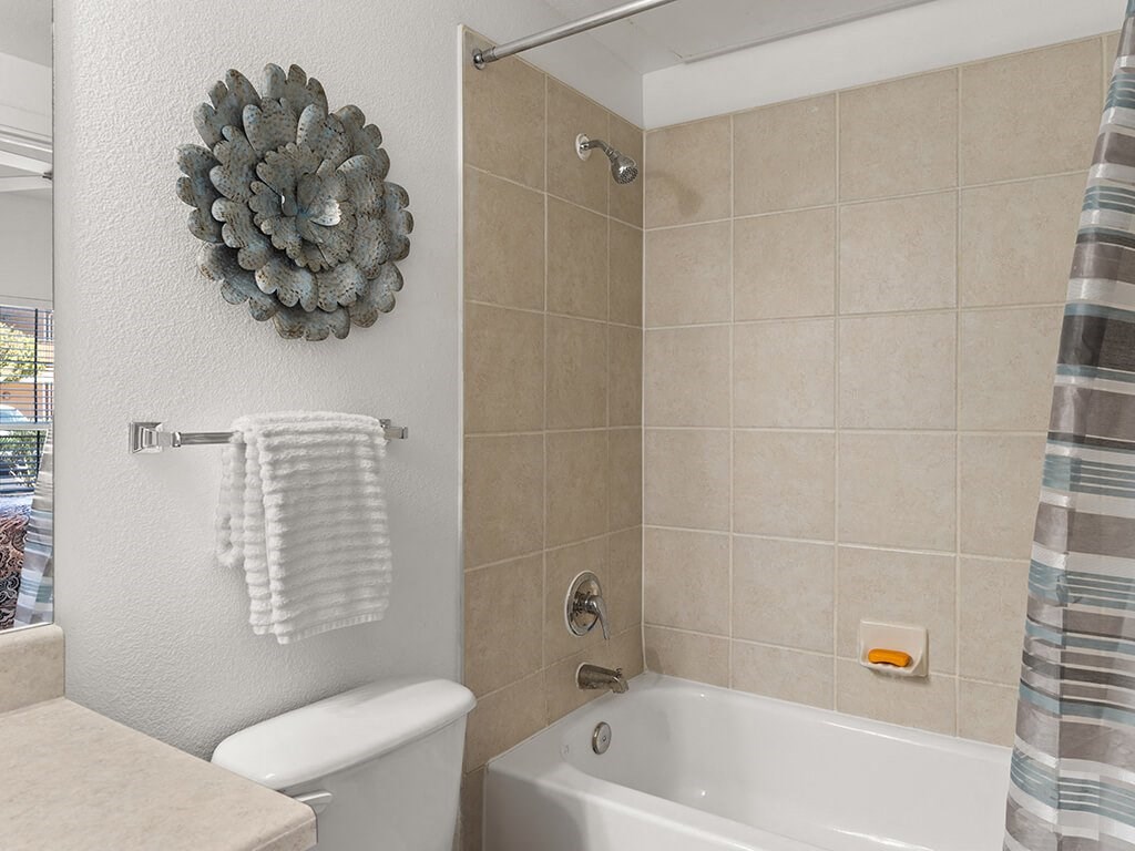 A bathroom with a white toilet, a white towel, and a white bathtub.