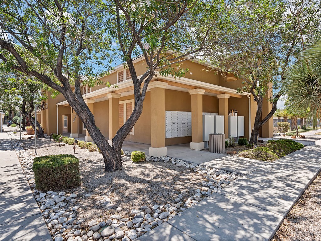 A beige house with a tree in front.