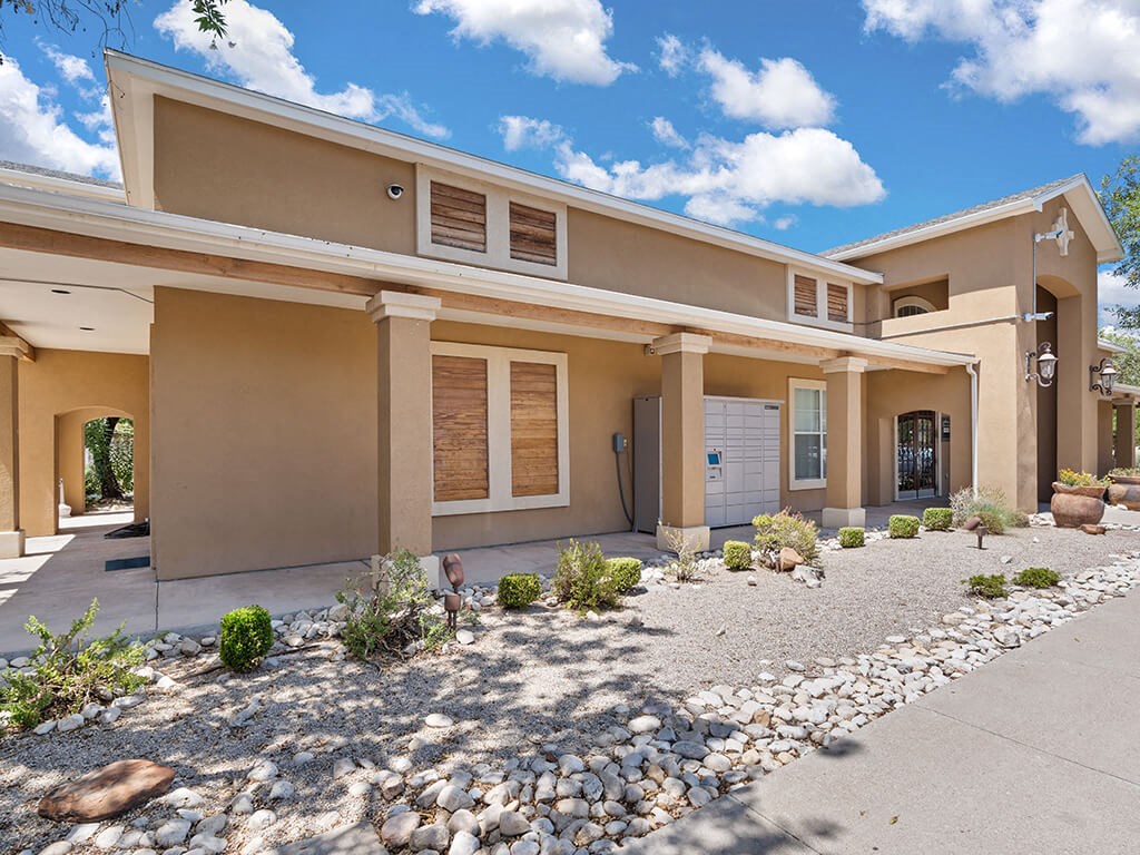 A modern house with a beige exterior and a gravel driveway.