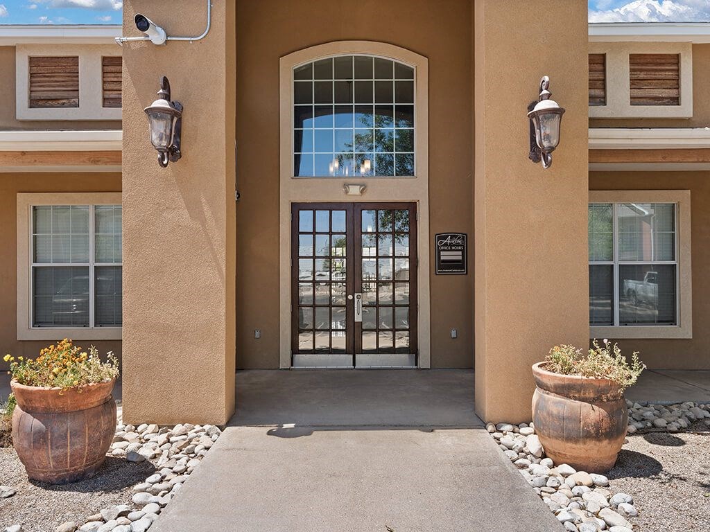 A building with a brown door and two lanterns on either side.