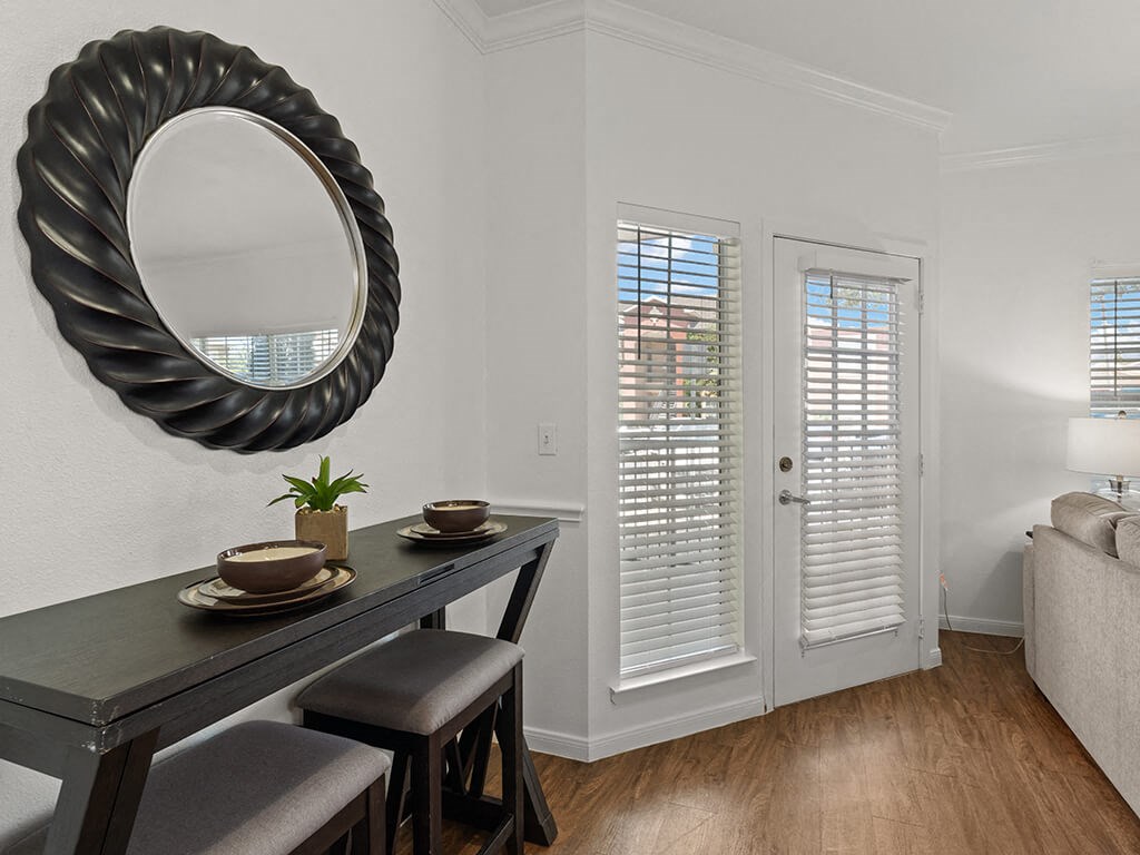 A black dining table with two chairs and a mirror above it.