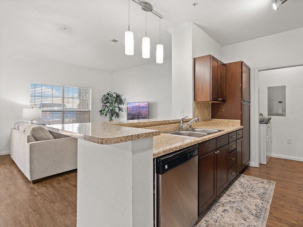 A modern kitchen with a marble countertop and dark wood cabinets.