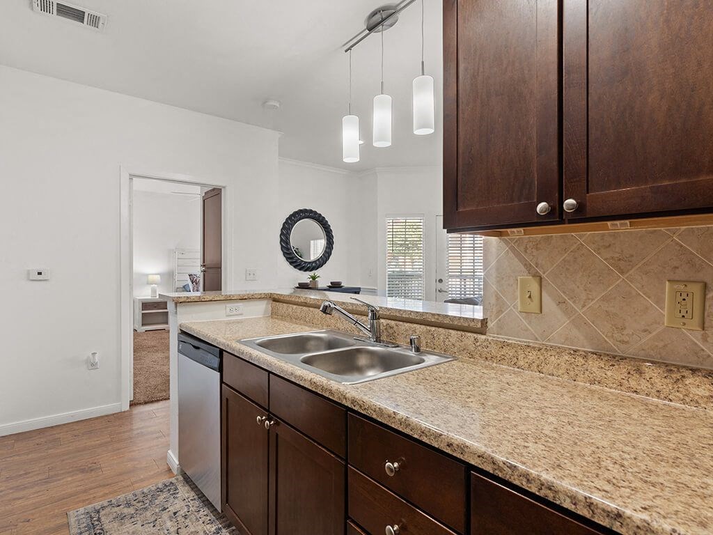 A kitchen with brown cabinets and granite countertops.