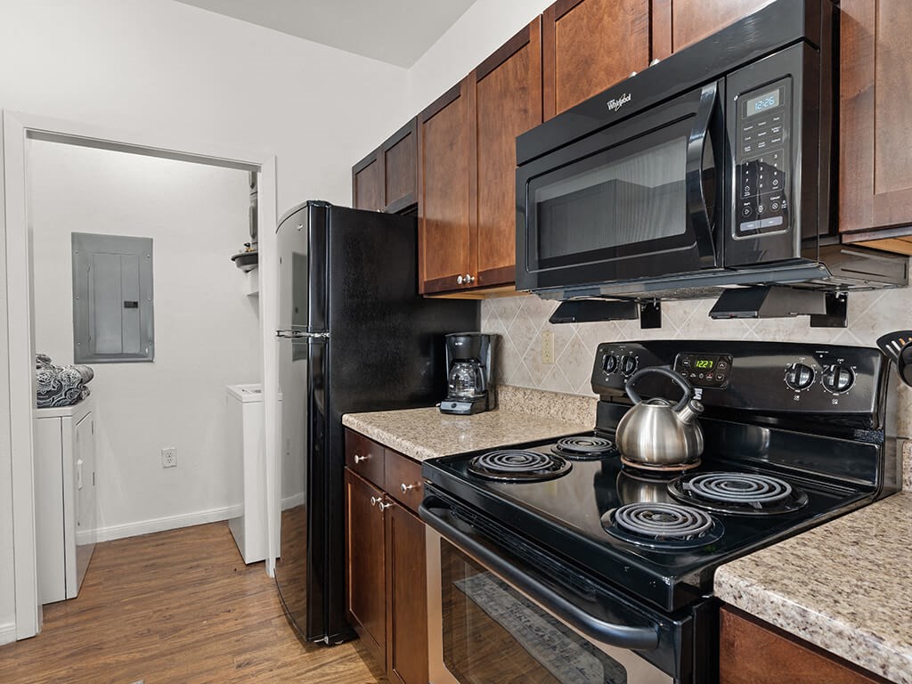 A black microwave oven is mounted above a black stove.