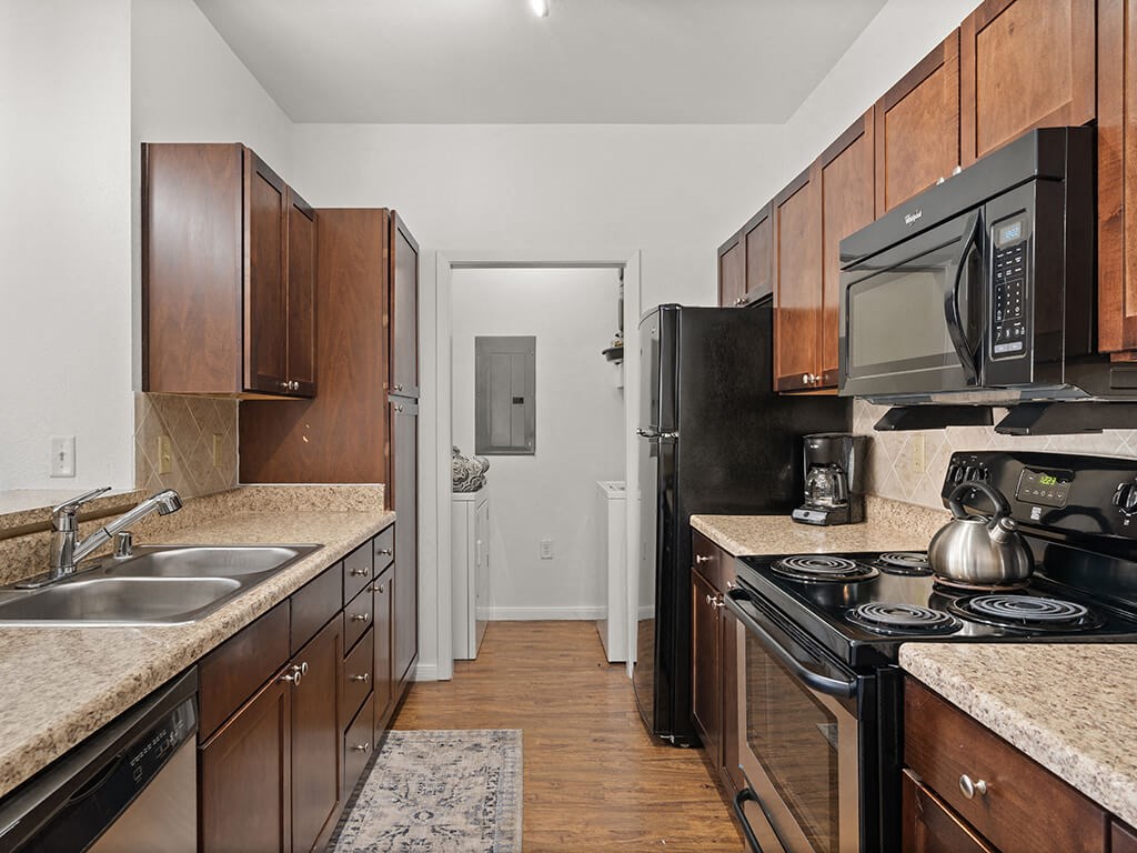 A kitchen with black appliances and wooden cabinets.