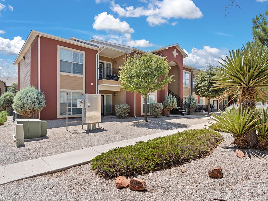 A red and beige apartment building with a landscaped front yard.