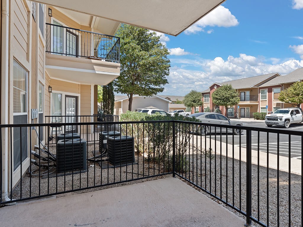 A black metal fence surrounds a patio with a table and chairs.