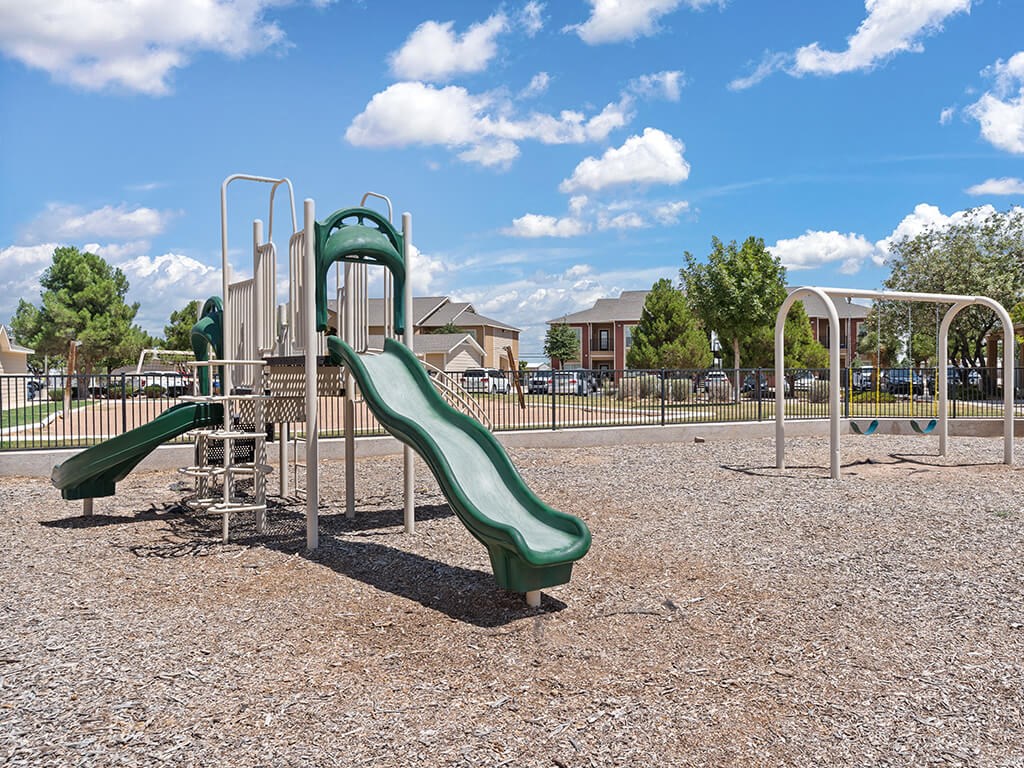A playground with a green slide and a metal structure.