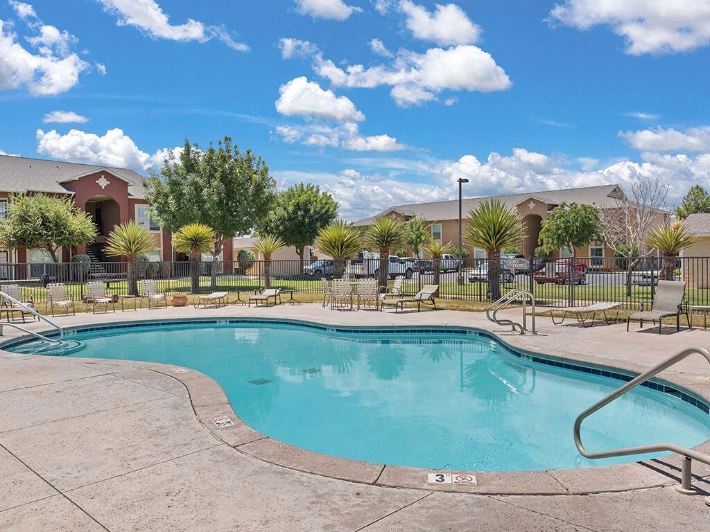 A swimming pool surrounded by a fence and chairs.