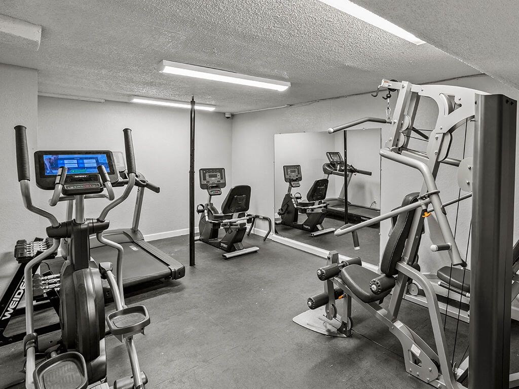 a gym with various machines and weights in a room