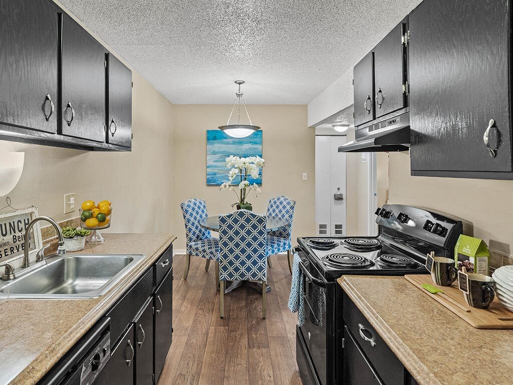 a kitchen with black appliances and a table with chairs
