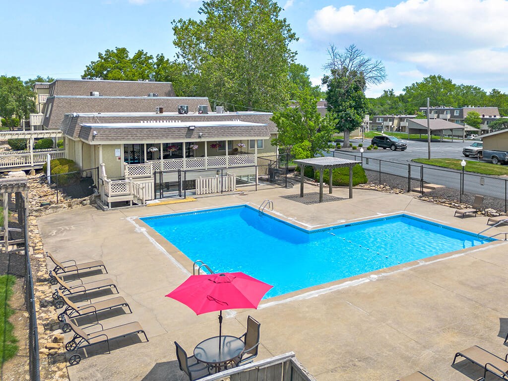 a swimming pool with an umbrella in front of a house