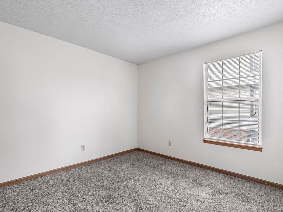 a bedroom with white walls and a window