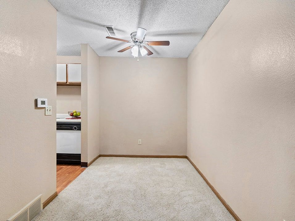 dining room with a ceiling fan and a kitchen in the background