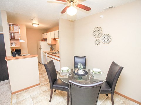 a dining room with a table and chairs and a kitchen in the background