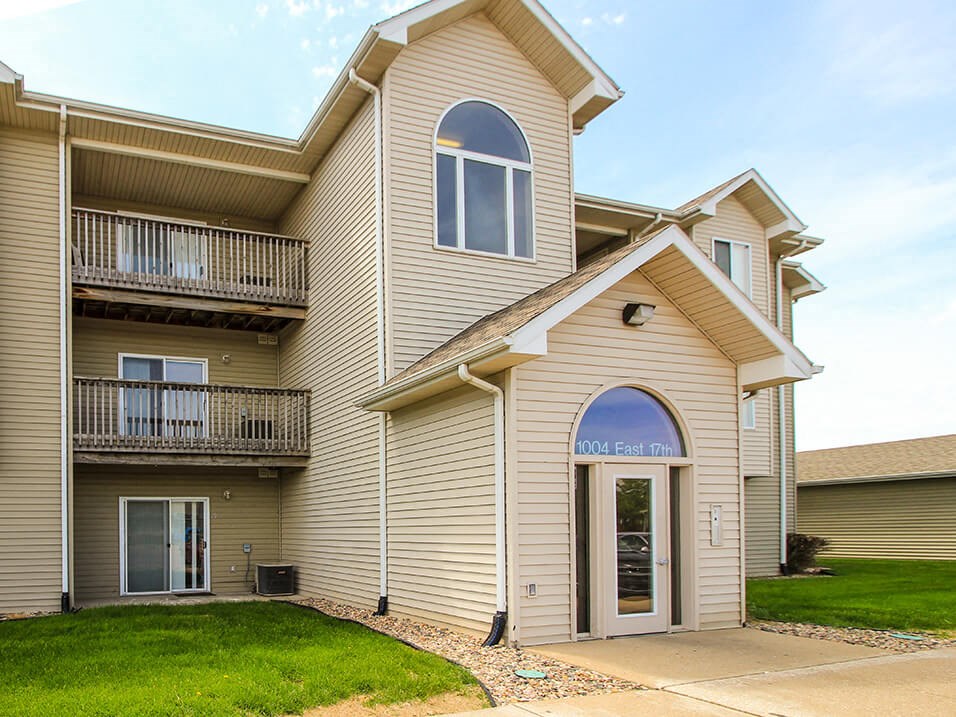 a building with tan siding and a green lawn