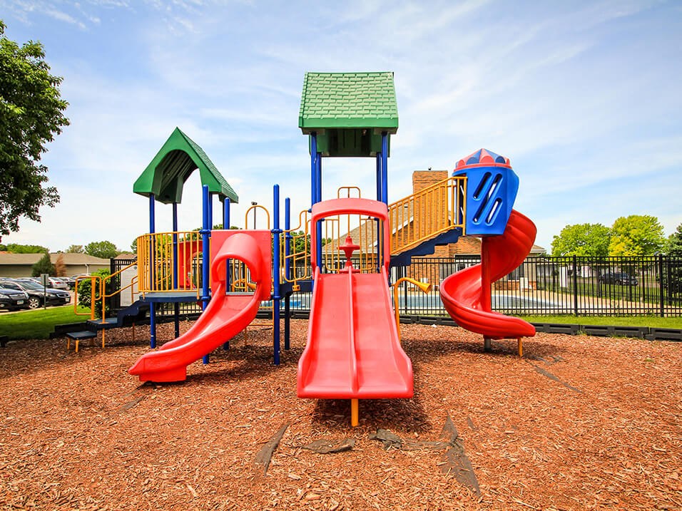 a playground with a red slide and a yellow and blue slide