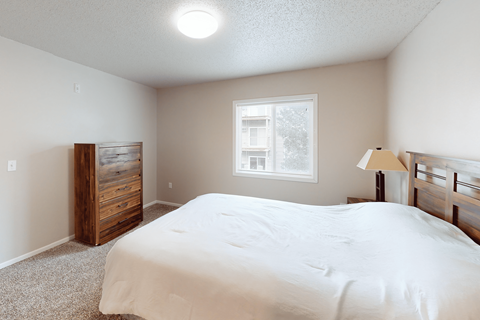 A bedroom with a bed, dresser, and window.