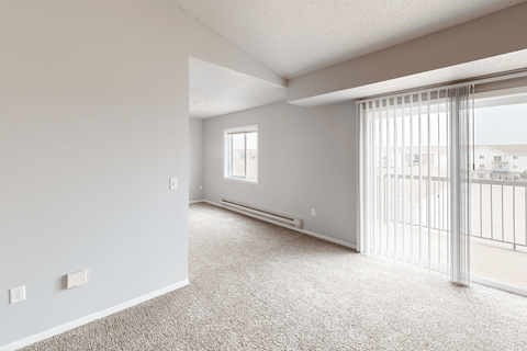 A spacious room with a sliding glass door leading to a balcony.