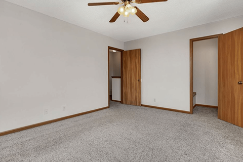 an empty living room with a ceiling fan and a door to a closet