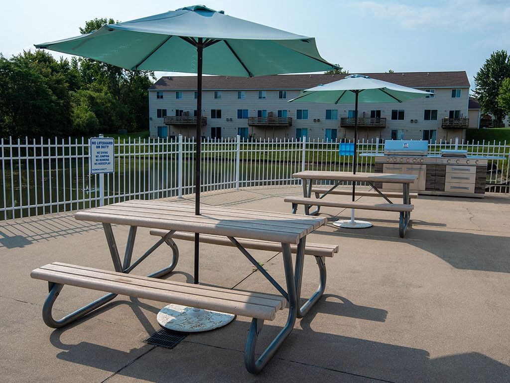 two picnic tables with umbrellas in a park