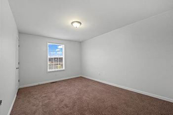 an empty room with a window and a carpet