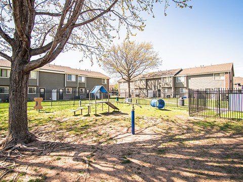 A playground area with a swing set and a slide in front of apartment buildings.