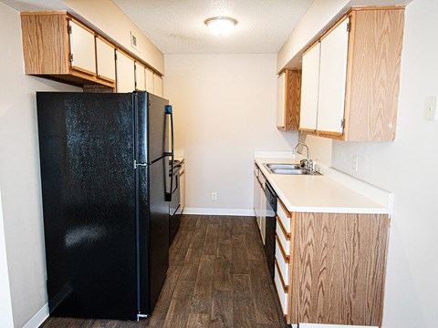 A black fridge in a kitchen with wooden cabinets.