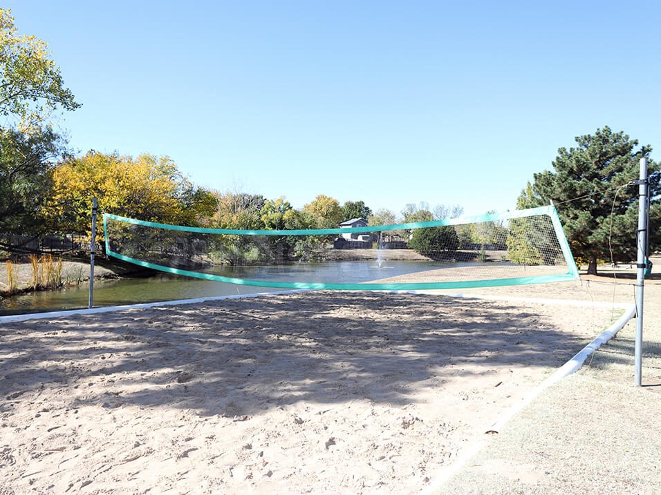 beach volleyball court alongside stocked fishing pond