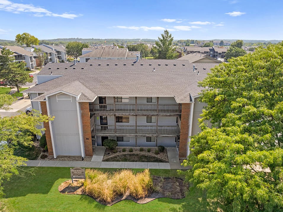 an aerial view of a building with a yard and trees