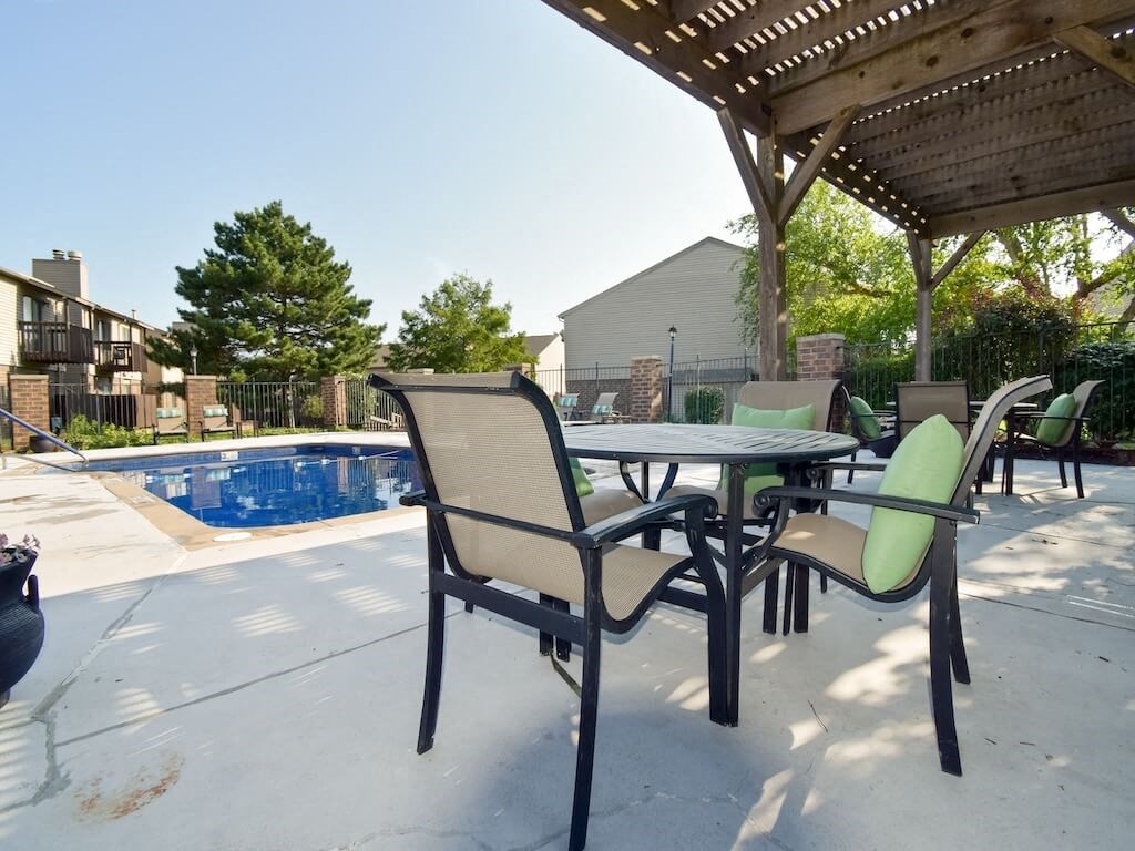 a patio with a table and chairs next to a pool