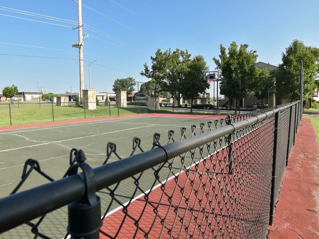 a tennis court with a fence and trees