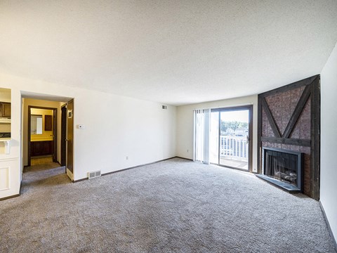 an empty living room with a fireplace and a balcony