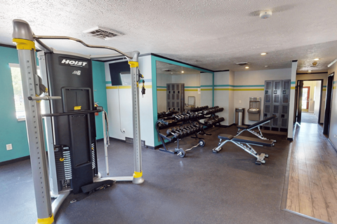 A gym with a variety of equipment including a weight machine and a bench press.