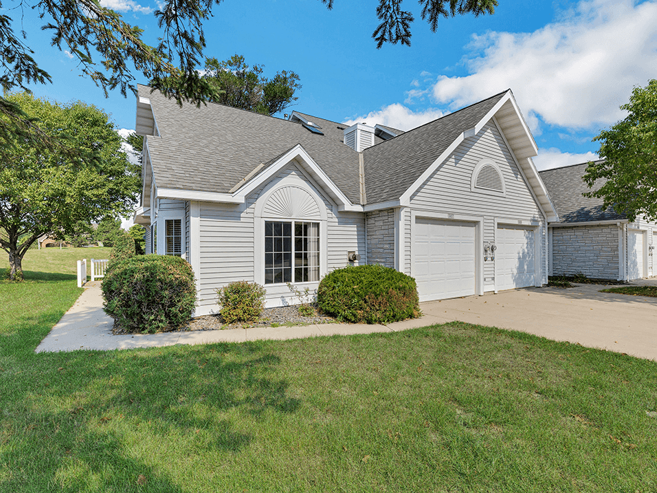 the front of a white house with a driveway and lawn