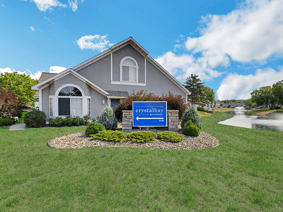 a home with a sign in front of a yard with a pond