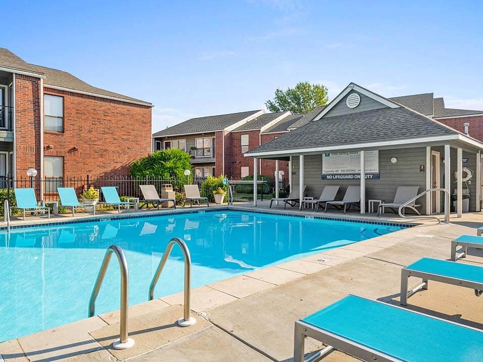 a swimming pool with tables and chairs in front of a building