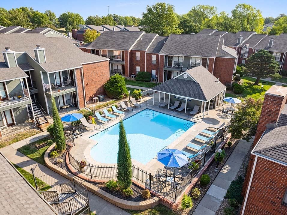 an aerial view of a swimming pool in front of an apartment building