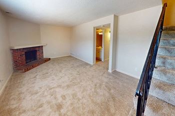 an empty living room with a fireplace and stairs