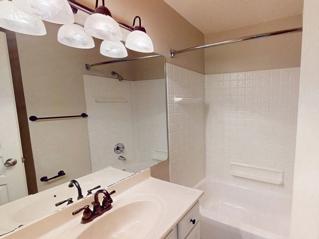 apartment bathroom with a sink and a shower and a mirror