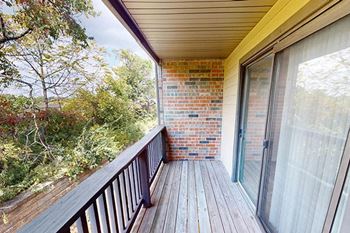 a balcony with a sliding glass door and a brick wall
