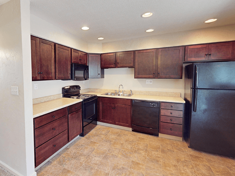 A kitchen with brown cabinets and black appliances.