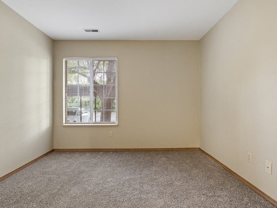 apartment bedroom with a window and carpet