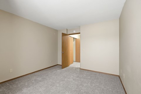 A room with a carpeted floor and a wooden door.