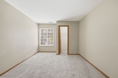 A room with a carpeted floor and a door leading to another room.